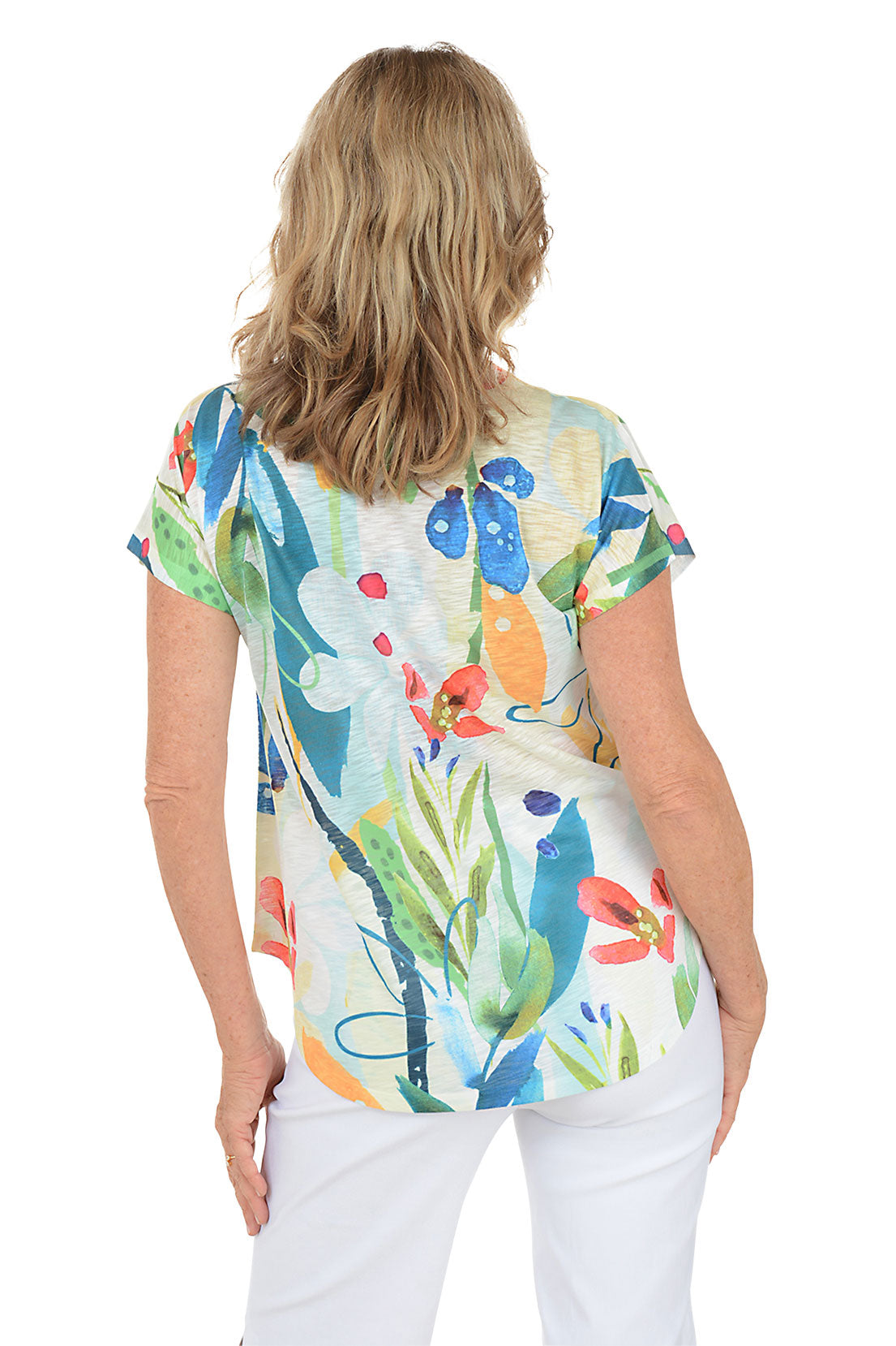 A woman wearing a short sleeve v-neck top with a tropical floral motif. Back shot.