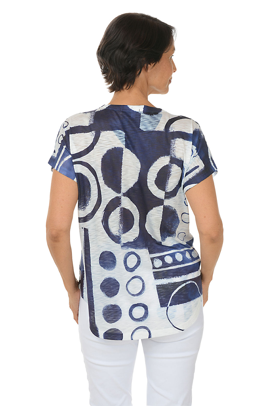 A woman wearing a short sleeve v-neck top with a round navy blue motif. Back shot.