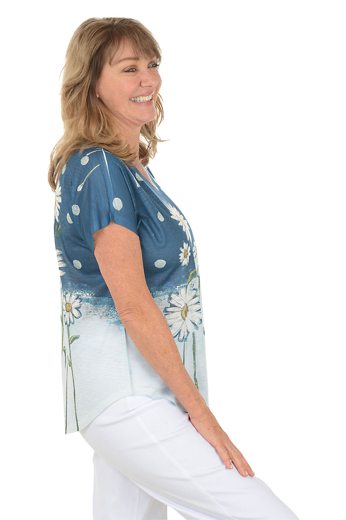 A woman wearing a blue and white daisy patterned short sleeve shirt. Side shot.