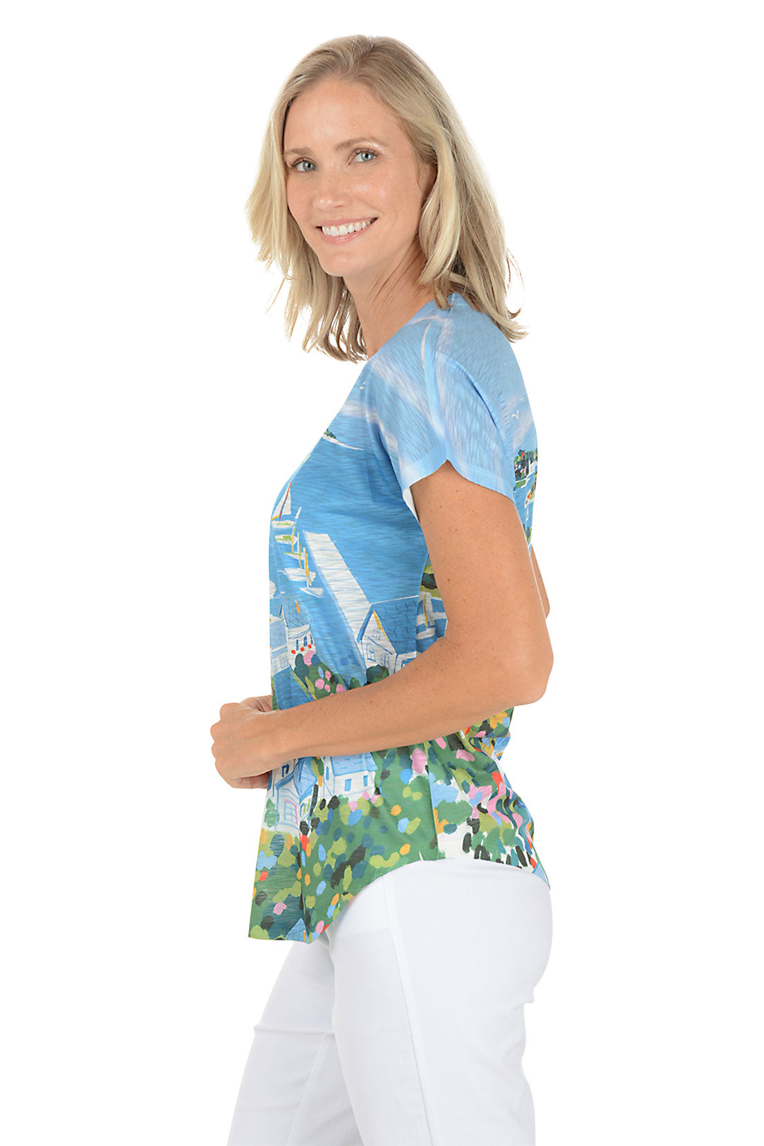 A woman wearing a blue short sleeve top with a sailboat painting. Side shot.