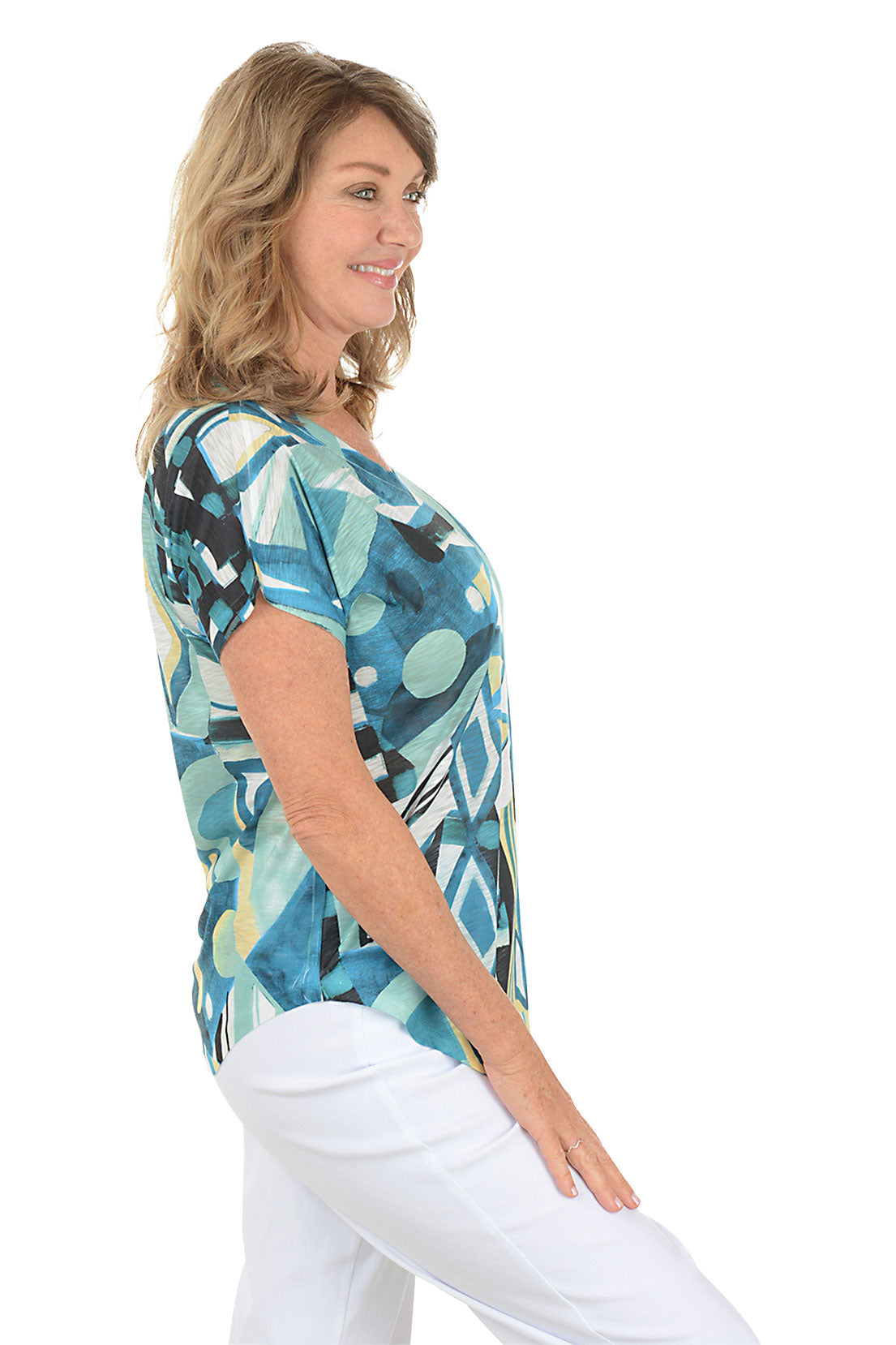 Woman wearing a colorful abstract patterned top on a white background. Side shot.