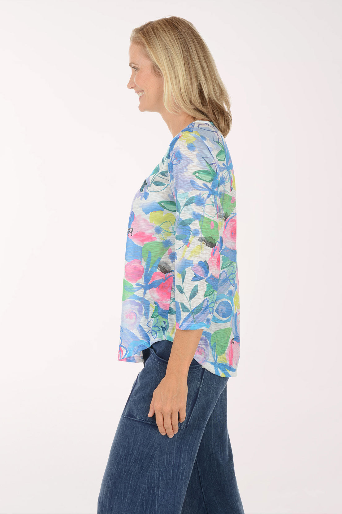 Woman wearing a colorful floral long-sleeve top against a white background