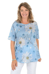 A woman wearing a blue short sleeve shirt with a daisy pattern.