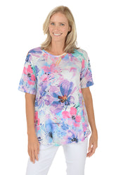 A woman wearing a purple short sleeve shirt with a floral pattern.