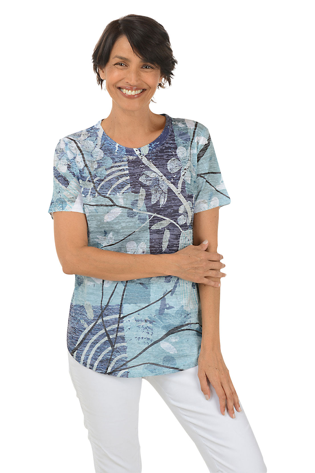 Woman wearing a blue floral patterned top and white pants on a white background