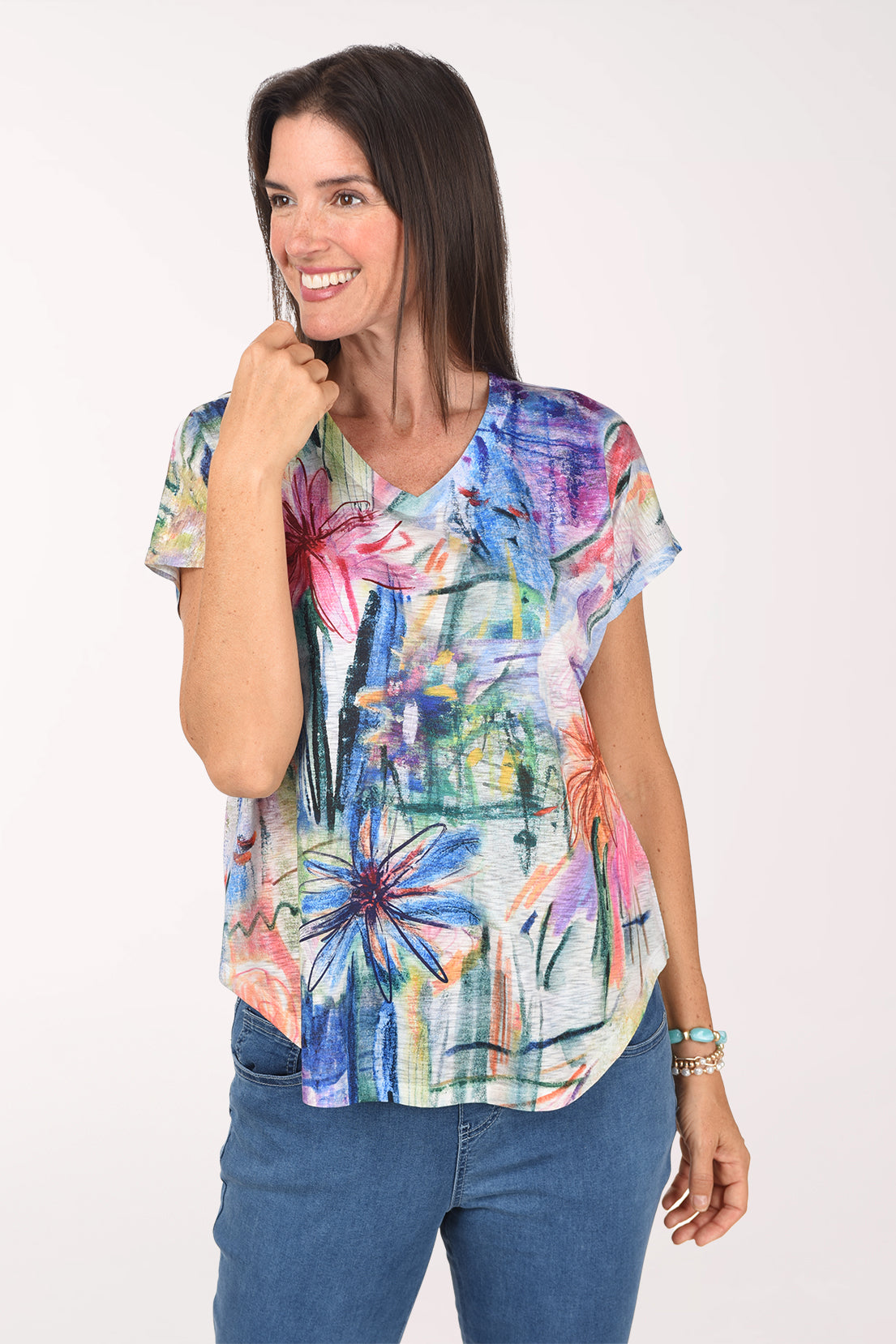 Model wearing the Jess and Jane Matisse Slub Knit Short Sleeve Top, painterly palms and blooms in cobalt, fuchsia and green, with jeans, front view