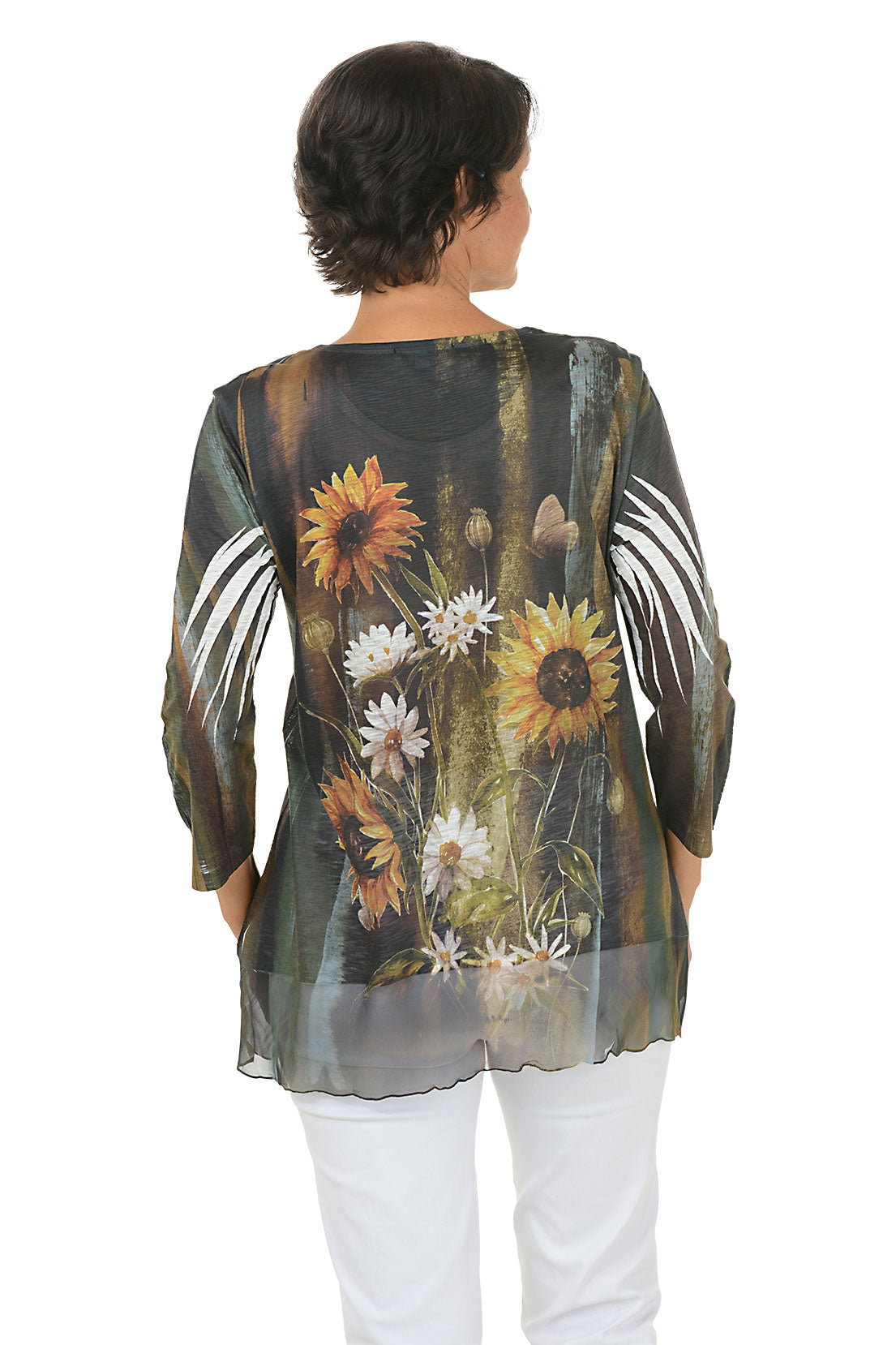 A back shot of a model wearing a floral print top with sunflowers and white flowers on a plain background.