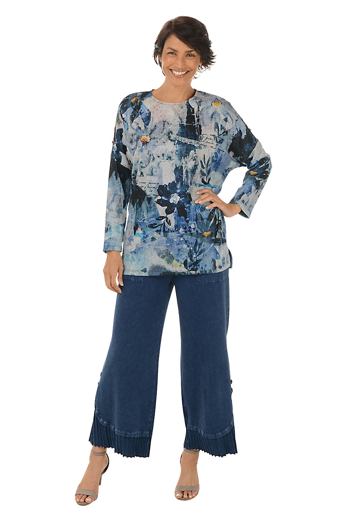 A full length shot of a model wearing a pair of wide-leg, pleated hem pants with a mineral wash design. The pants have a high waist with a 1 1/2 inch elasticized waistband, dual front patch pockets, and a double button embellishment at the pleated hemline.