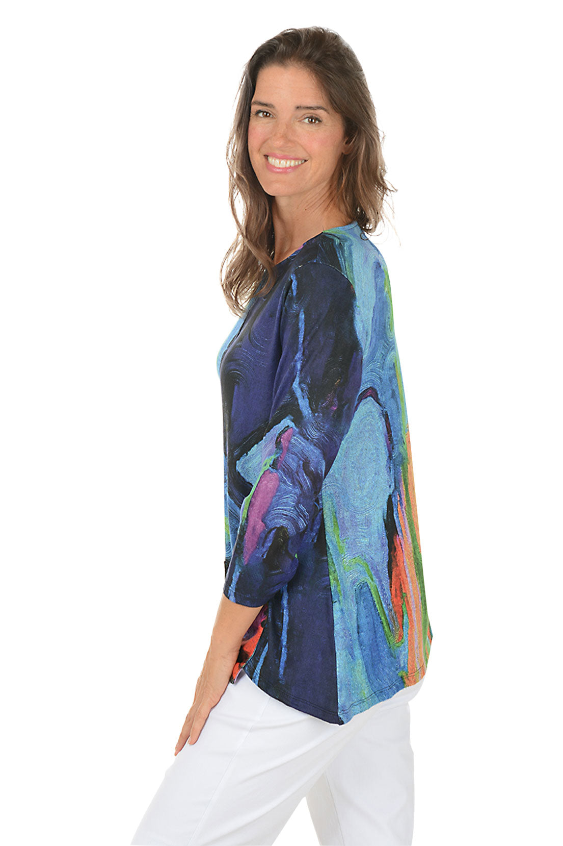 Woman wearing a colorful long-sleeve top with abstract design on a white background. Side shot.