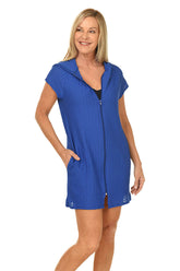 A front shot of a model wearing a blue hooded waffle-knit full-zip cover-up with short sleeves and double front pockets.