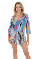 A front shot of a model wearing a multicolored geometric patterned mesh tunic cover-up with a V-neckline and 3/4-length bell sleeves.