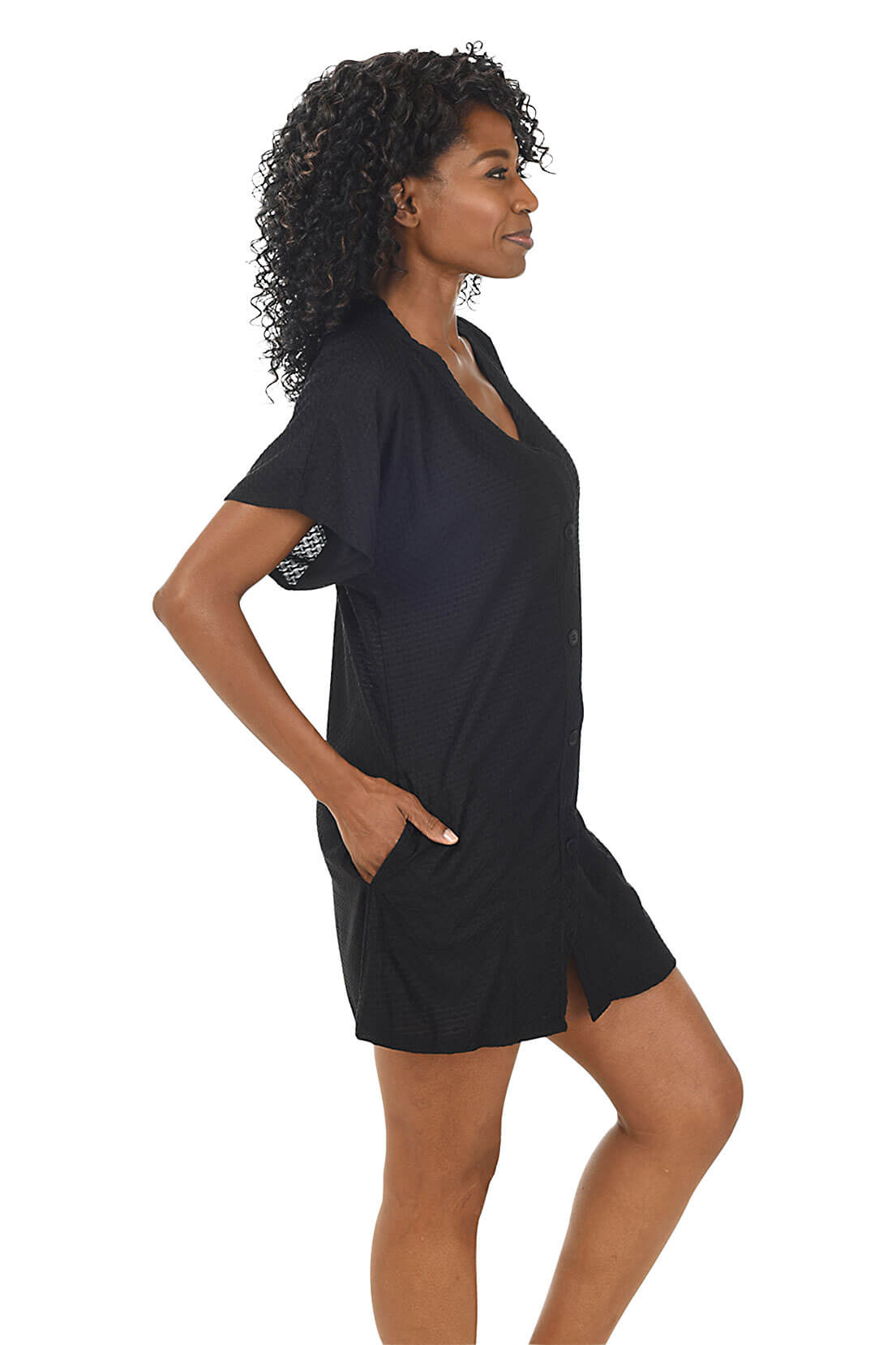 Woman wearing a black dress with a white background. Side shot.