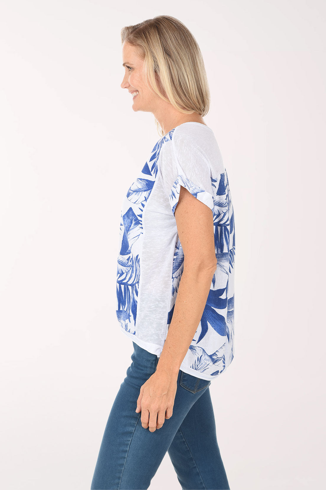 Woman wearing a blue and white patterned shirt with blue jeans on a white background