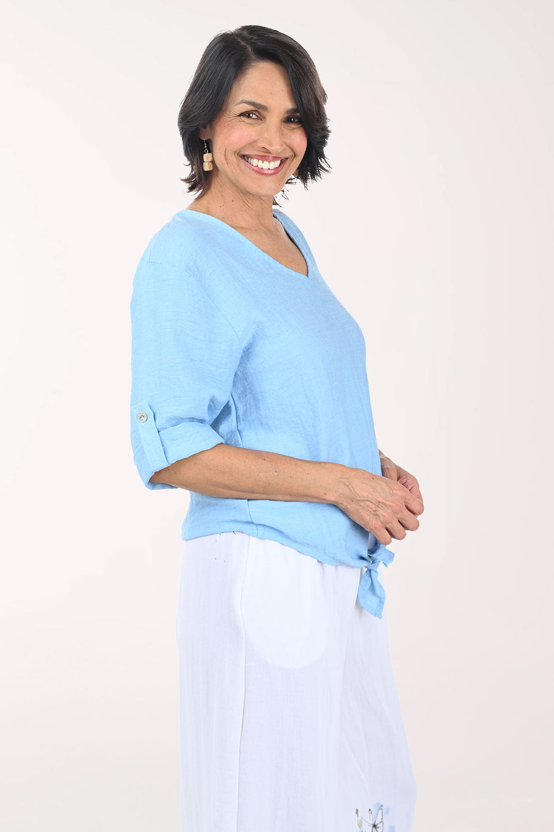Woman wearing a light blue top and white pants on a white background