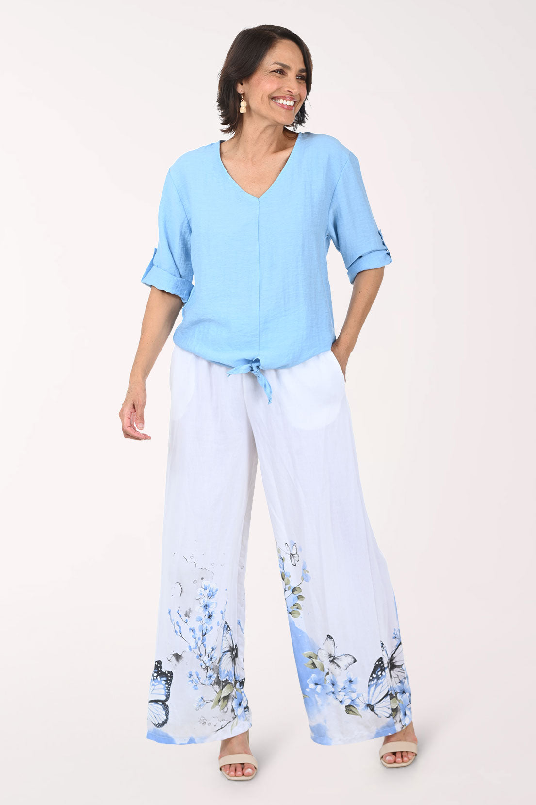 Woman wearing a light blue top and floral pants on a white background