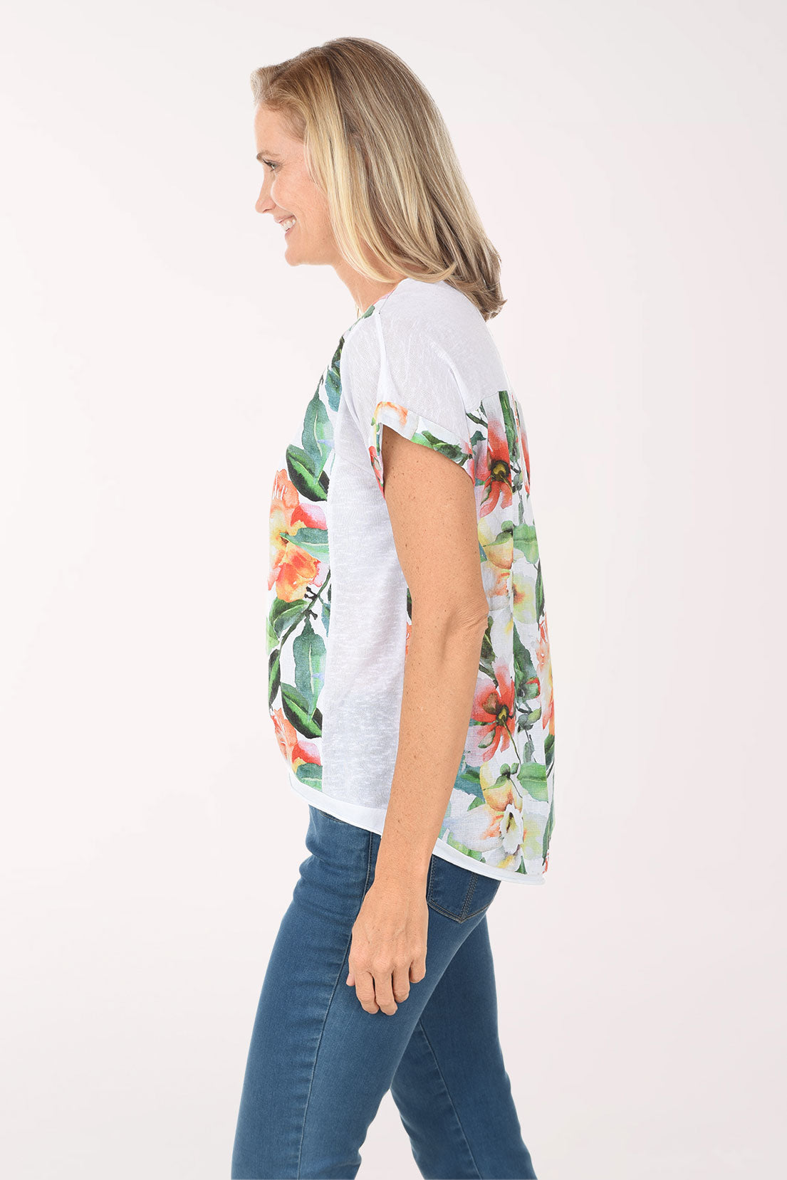 Woman wearing a white t-shirt with floral design and blue jeans on a white background