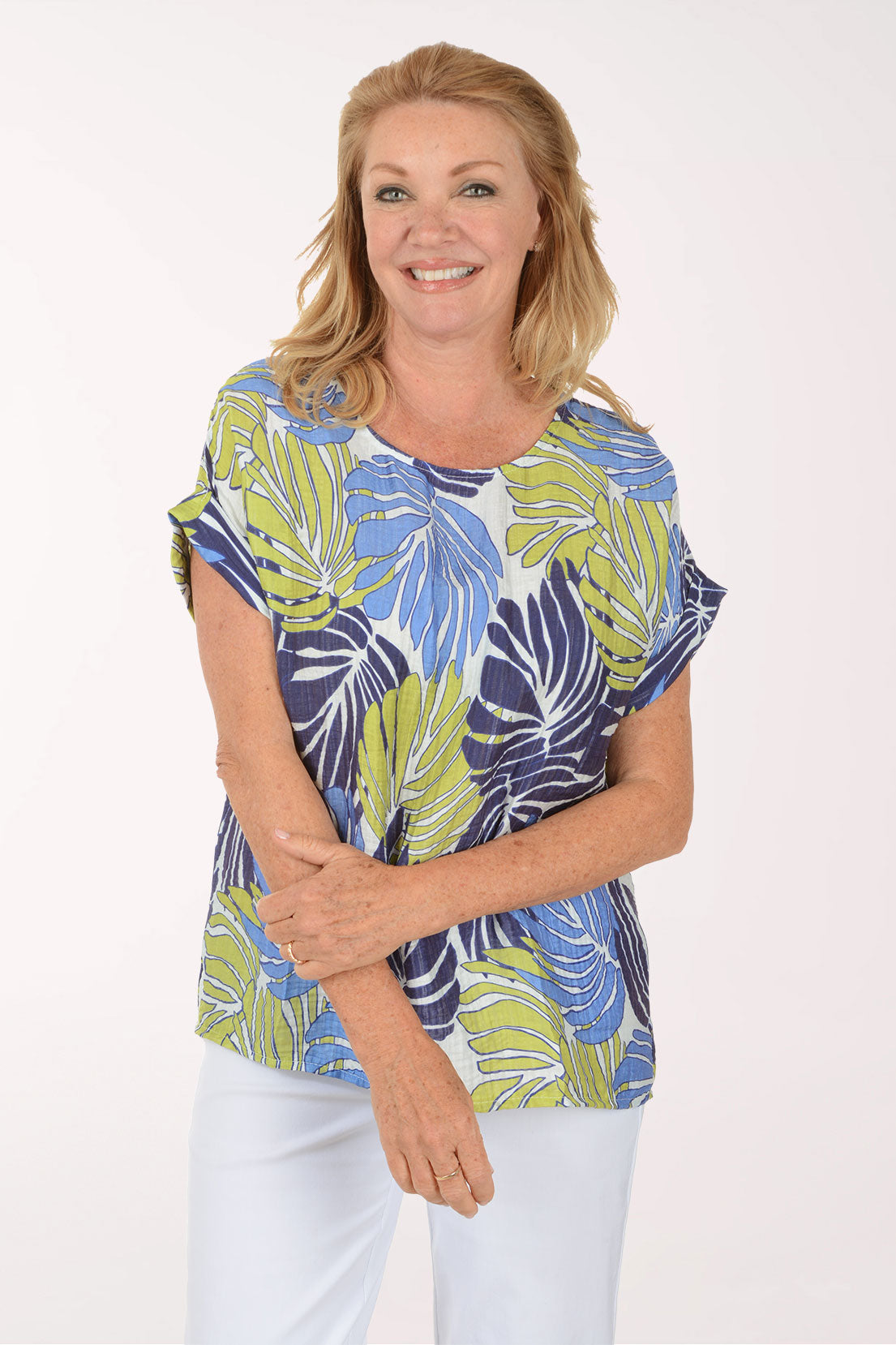 Woman wearing a colorful leaf-patterned top on a white background