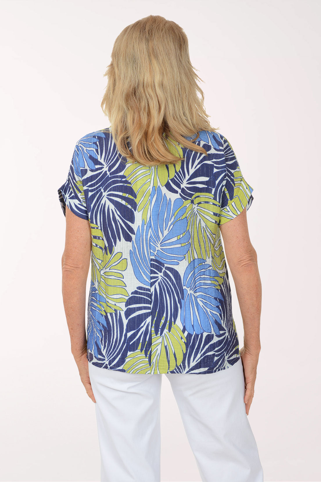 Woman wearing a colorful leaf-patterned top on a white background