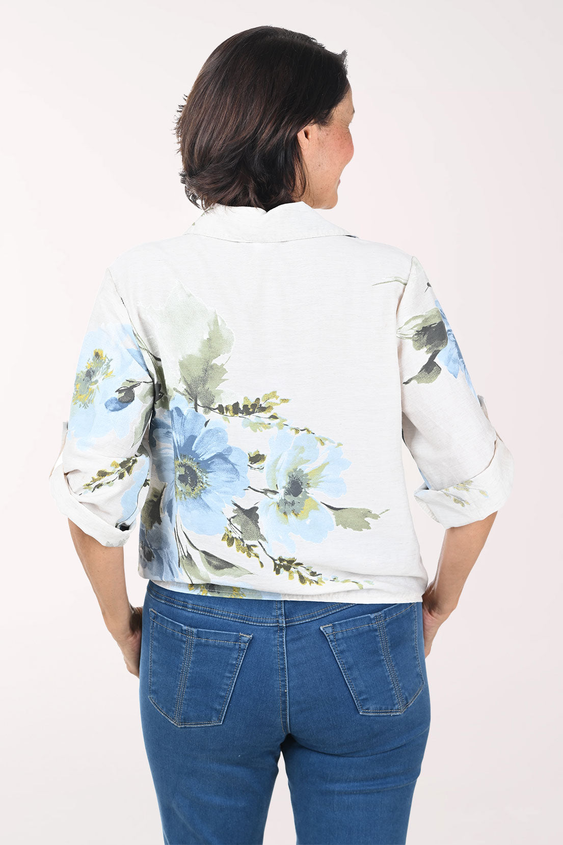 Woman wearing a beige floral blouse with rolled-up sleeves on a white background