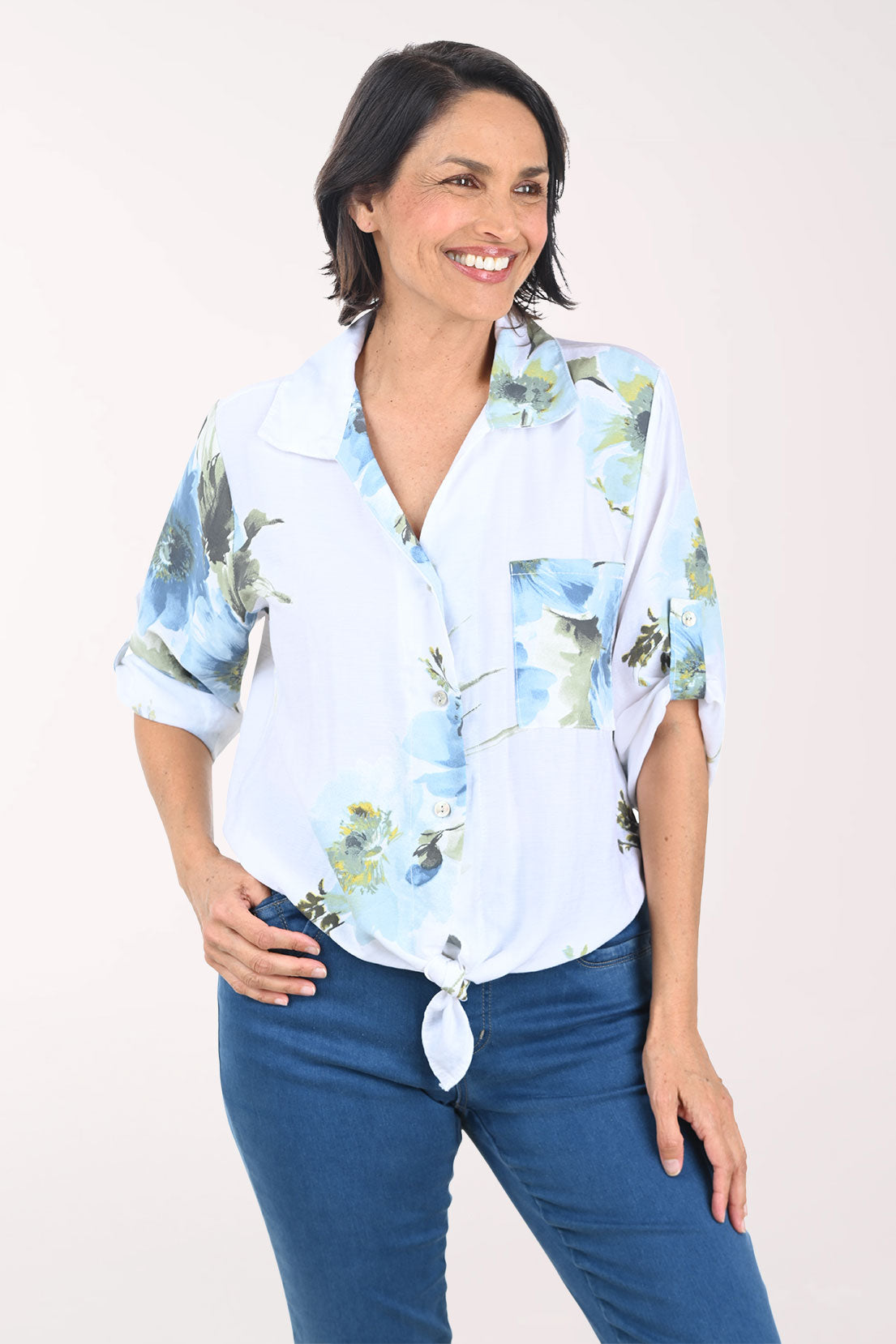 Woman wearing a white floral blouse with rolled-up sleeves on a white background