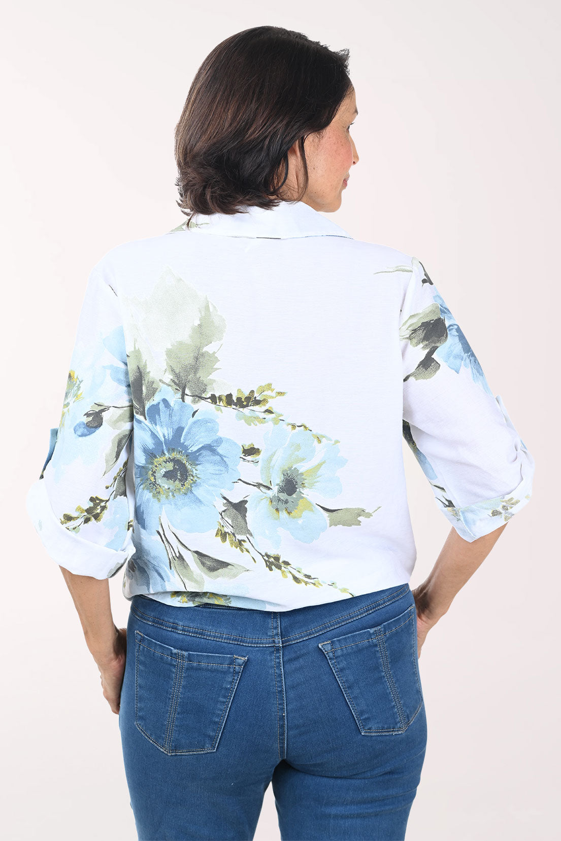 Woman wearing a white floral blouse with rolled-up sleeves on a white background