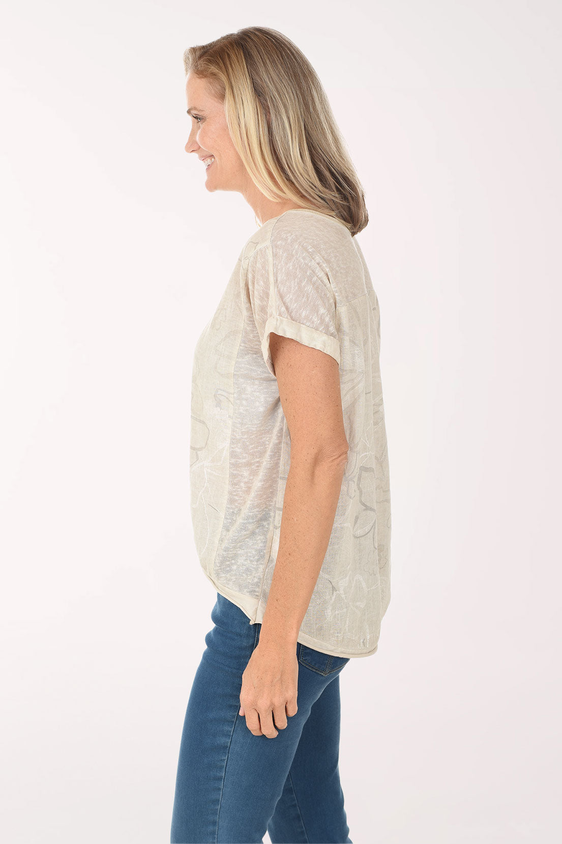 Woman wearing a beige lace top and blue jeans on a white background