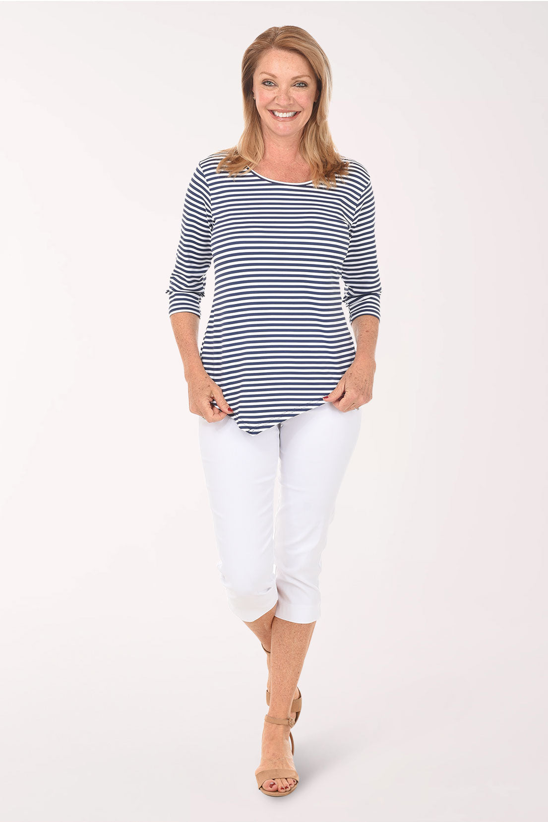 Woman wearing a blue and white striped top and white pants on a white background