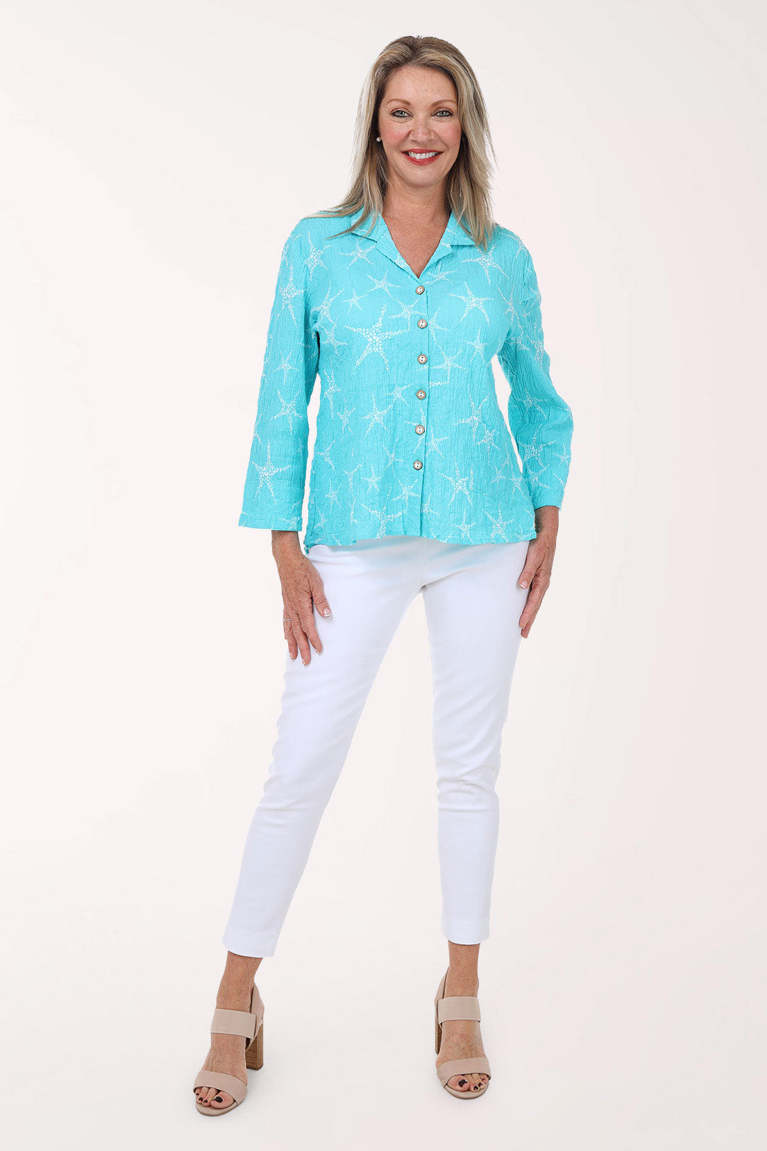 Woman wearing a turquoise blouse with white pants on a white background