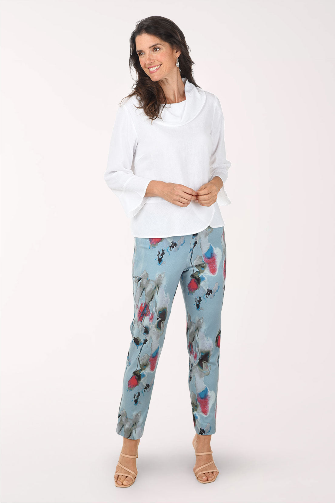 Woman wearing a white blouse and light blue pants with bird pattern on a white background