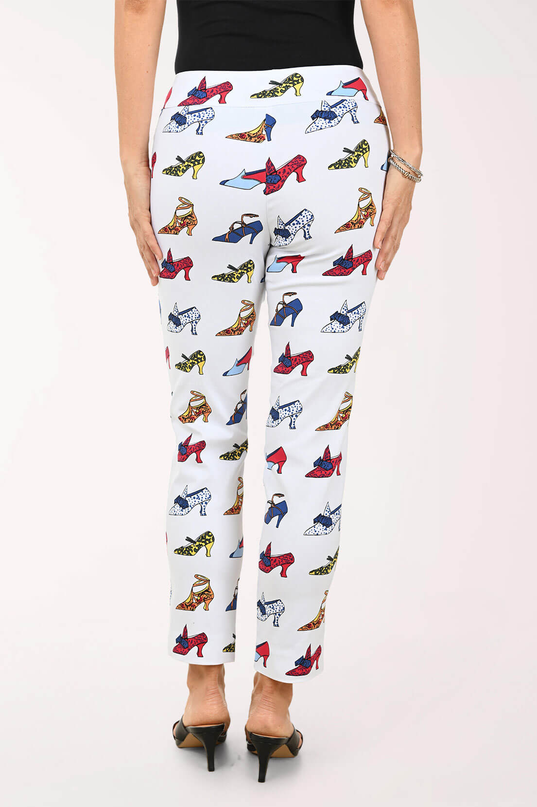 White pants with colorful high heel print worn by a person on a white background