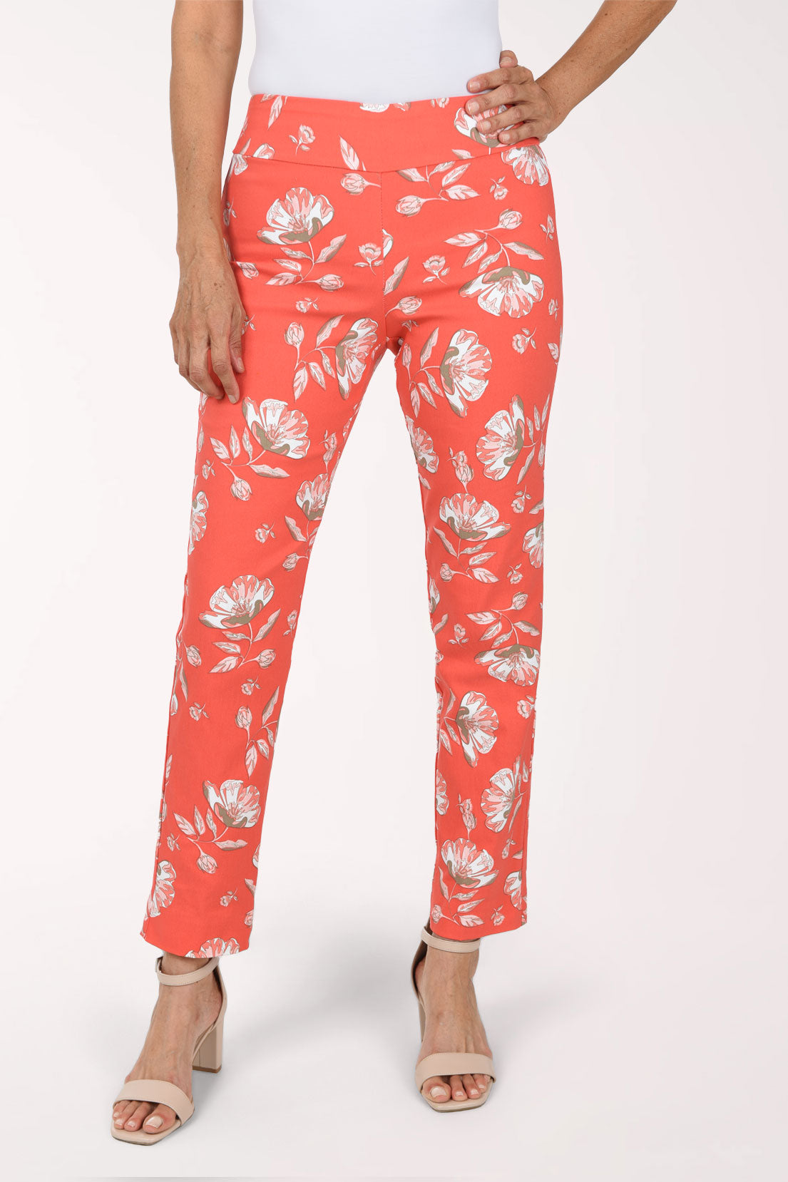Woman wearing tangerine orange pull on ankle pants with a white floral pattern