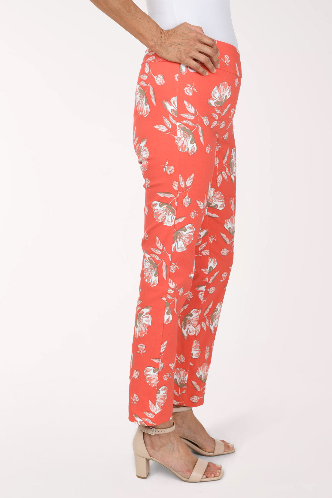 Woman wearing tangerine orange pull on ankle pants with a white floral pattern
