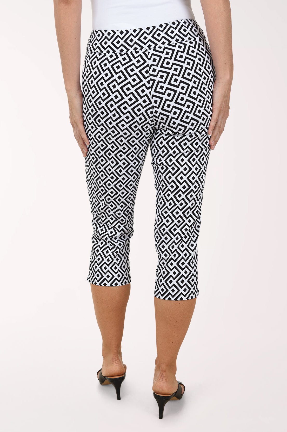 Person wearing black and white patterned capri pants on a white background