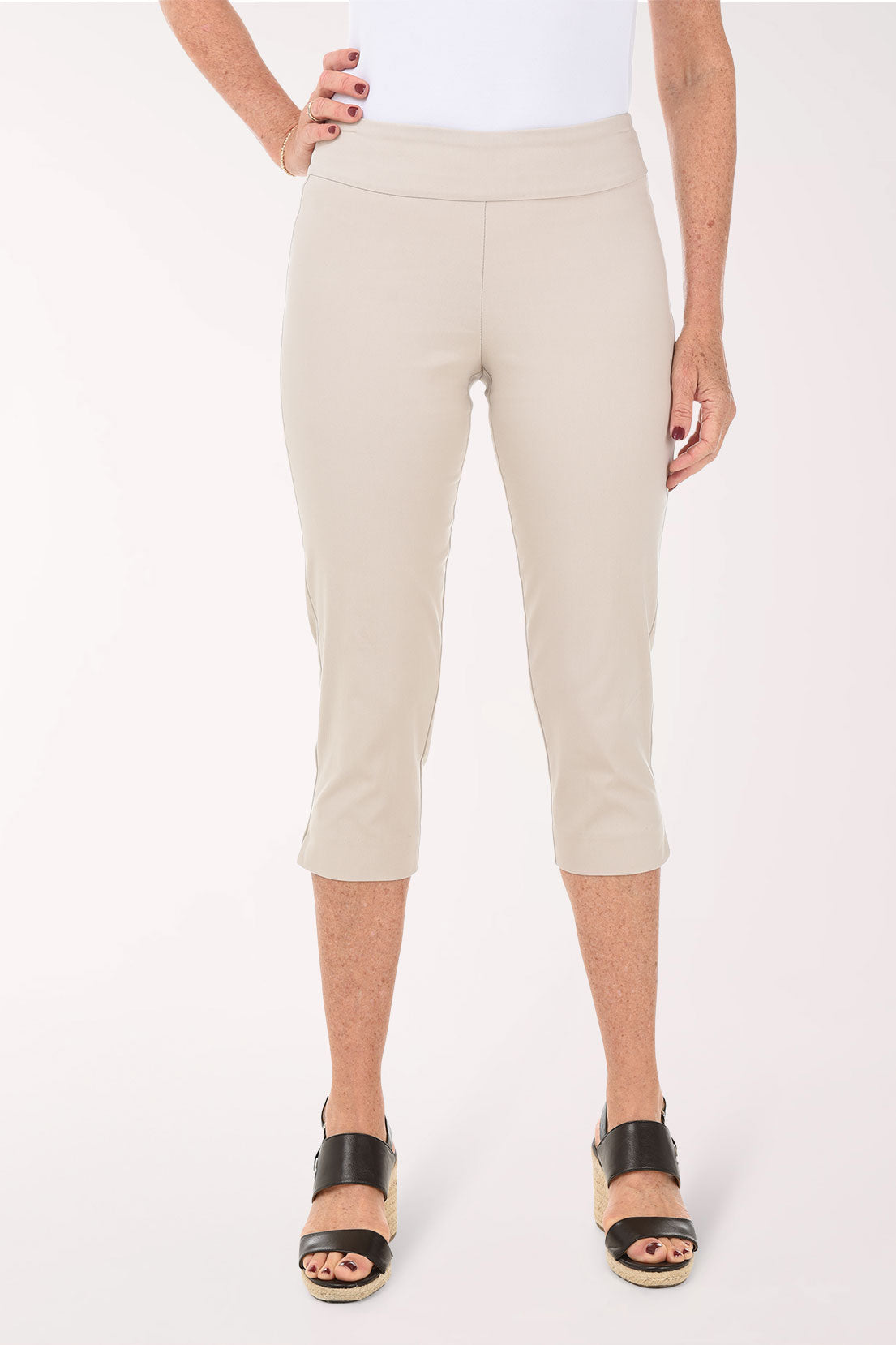 Person wearing beige capri pants on a white background