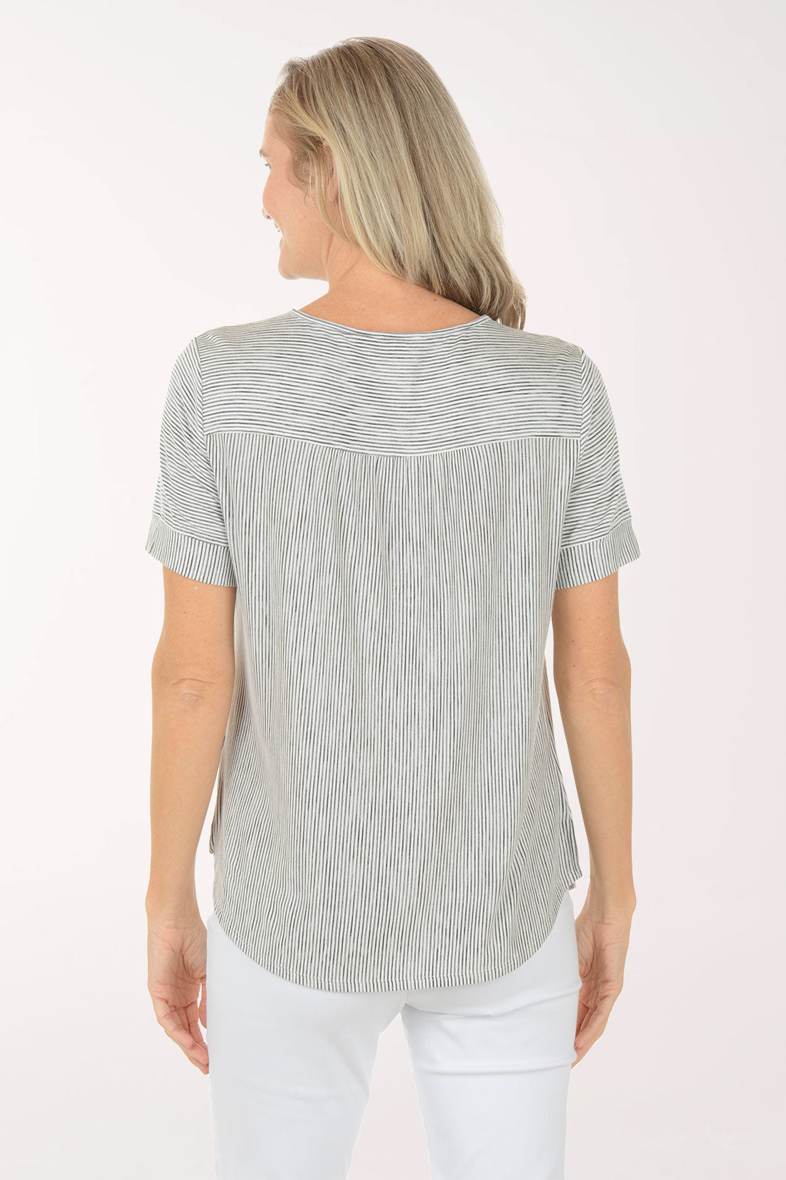 Woman wearing a black and white striped shirt and white pants on a white background
