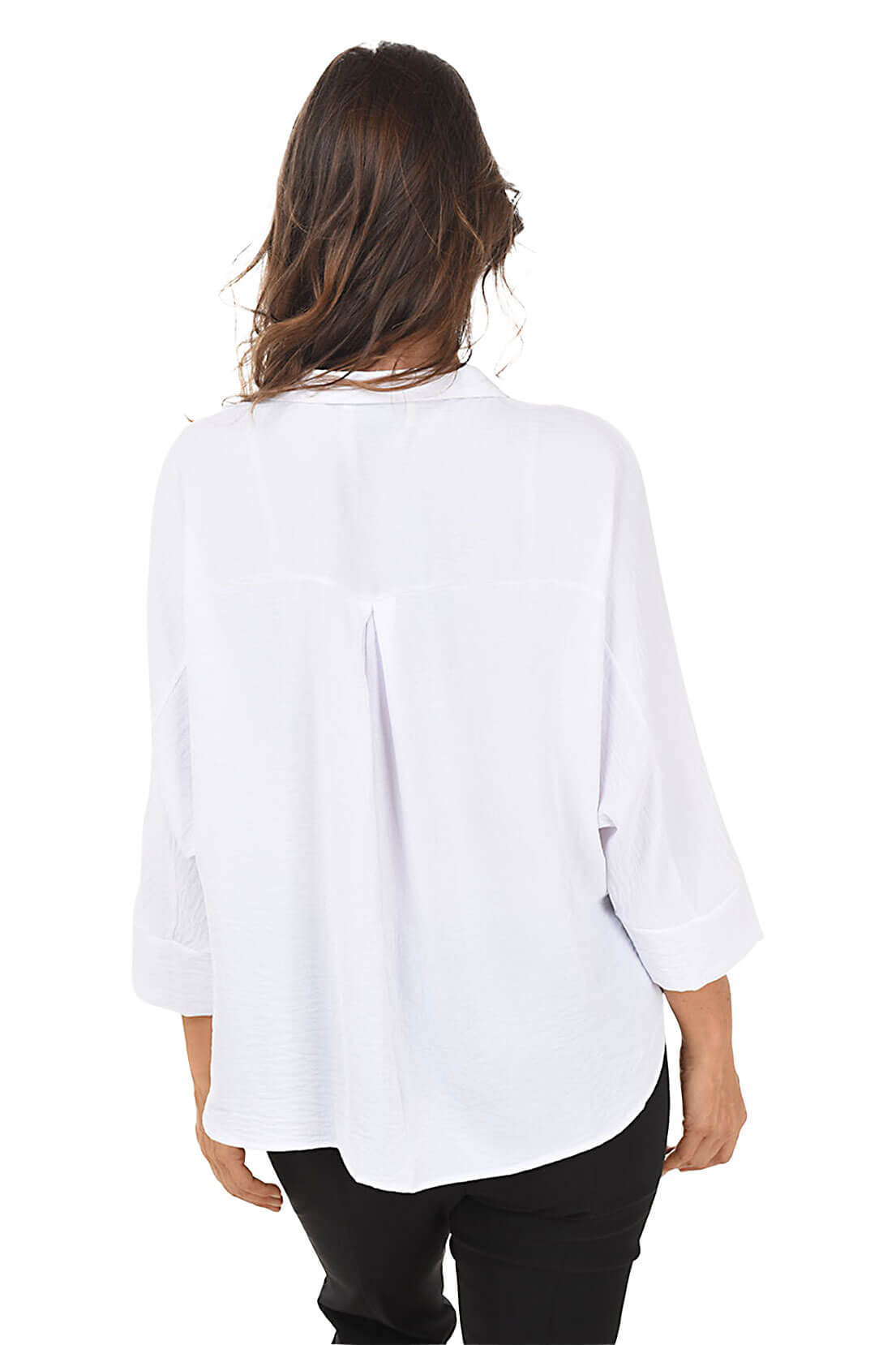 A back shot of a model wearing a white dolman sleeve blouse with a classic foldover collar and pearlescent button accents, paired with black pants.
