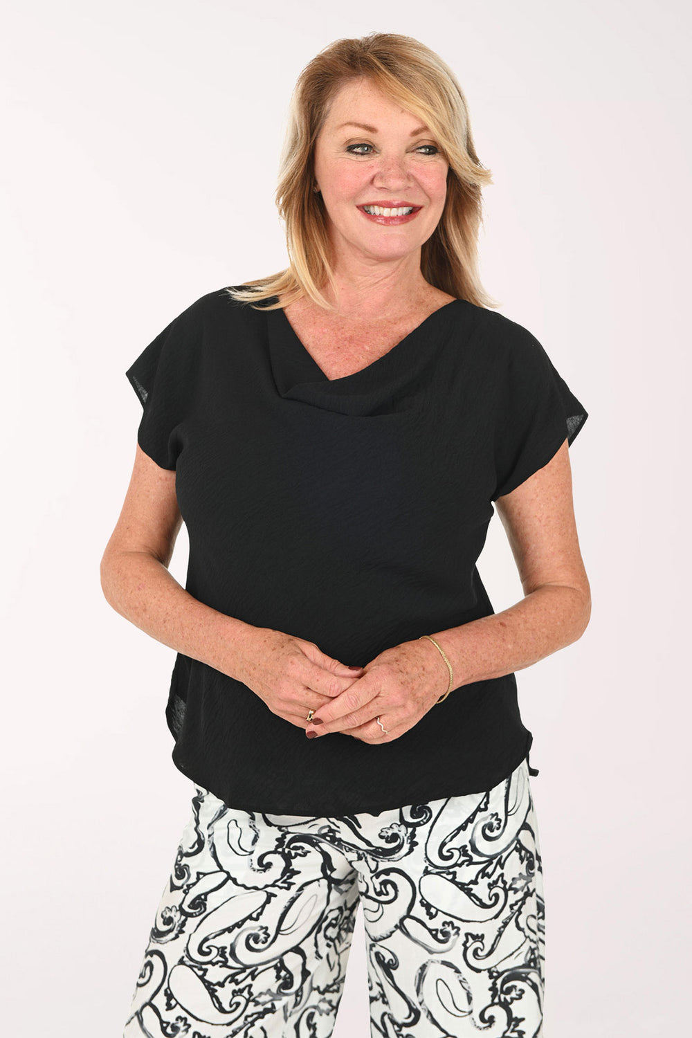Woman wearing a black cap sleeve tee with a draped neckline