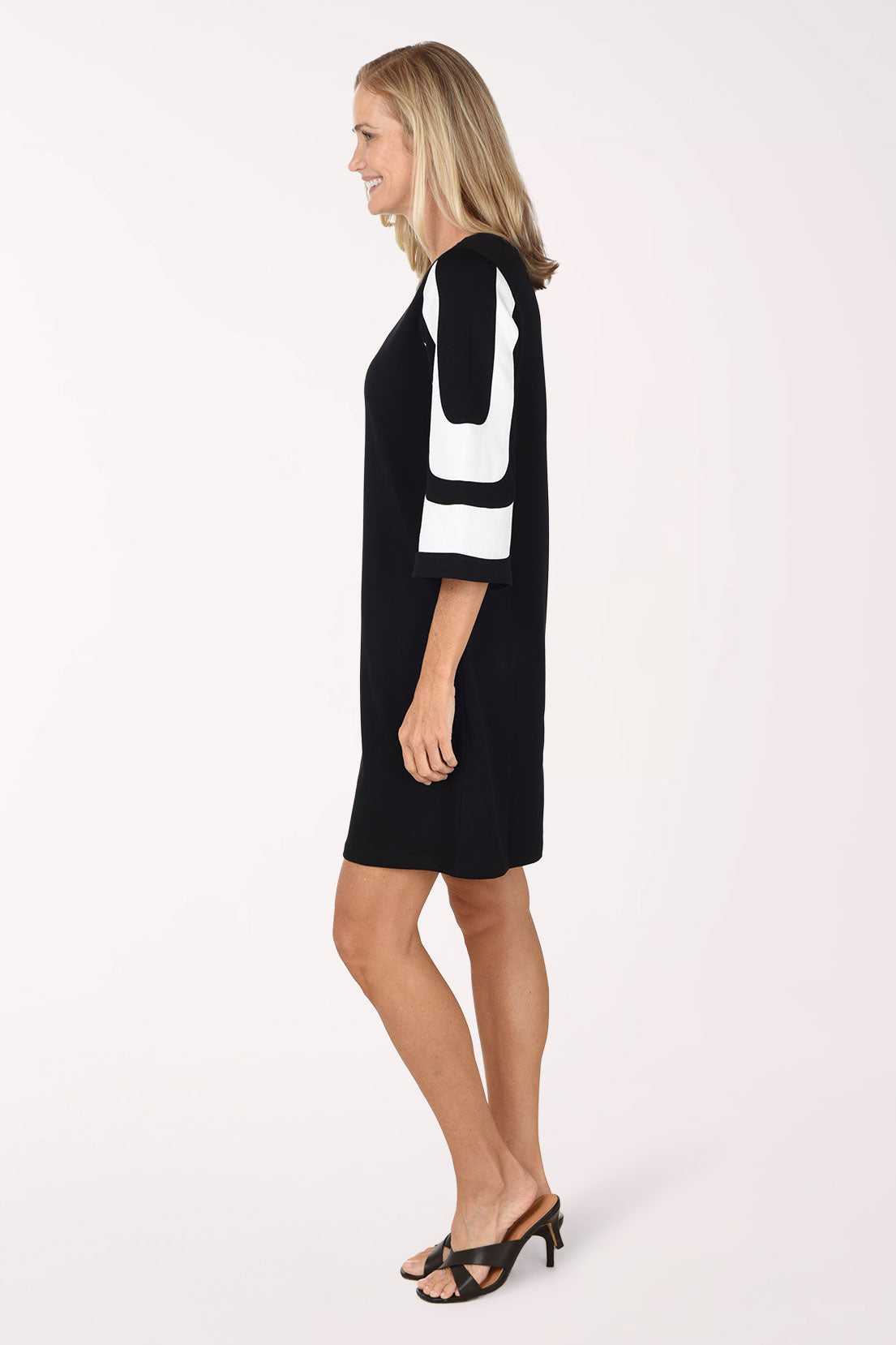 Side view of the Monochrome Mod Color Block Dress showing the flared sleeve with white color block bands and the straight hem.