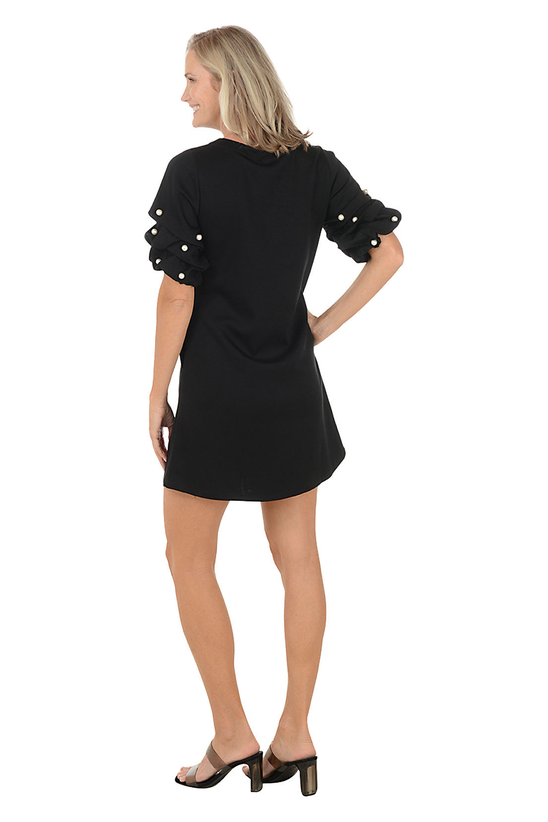 Woman wearing a black dress with pearl embellishments on a white background. Back shot.