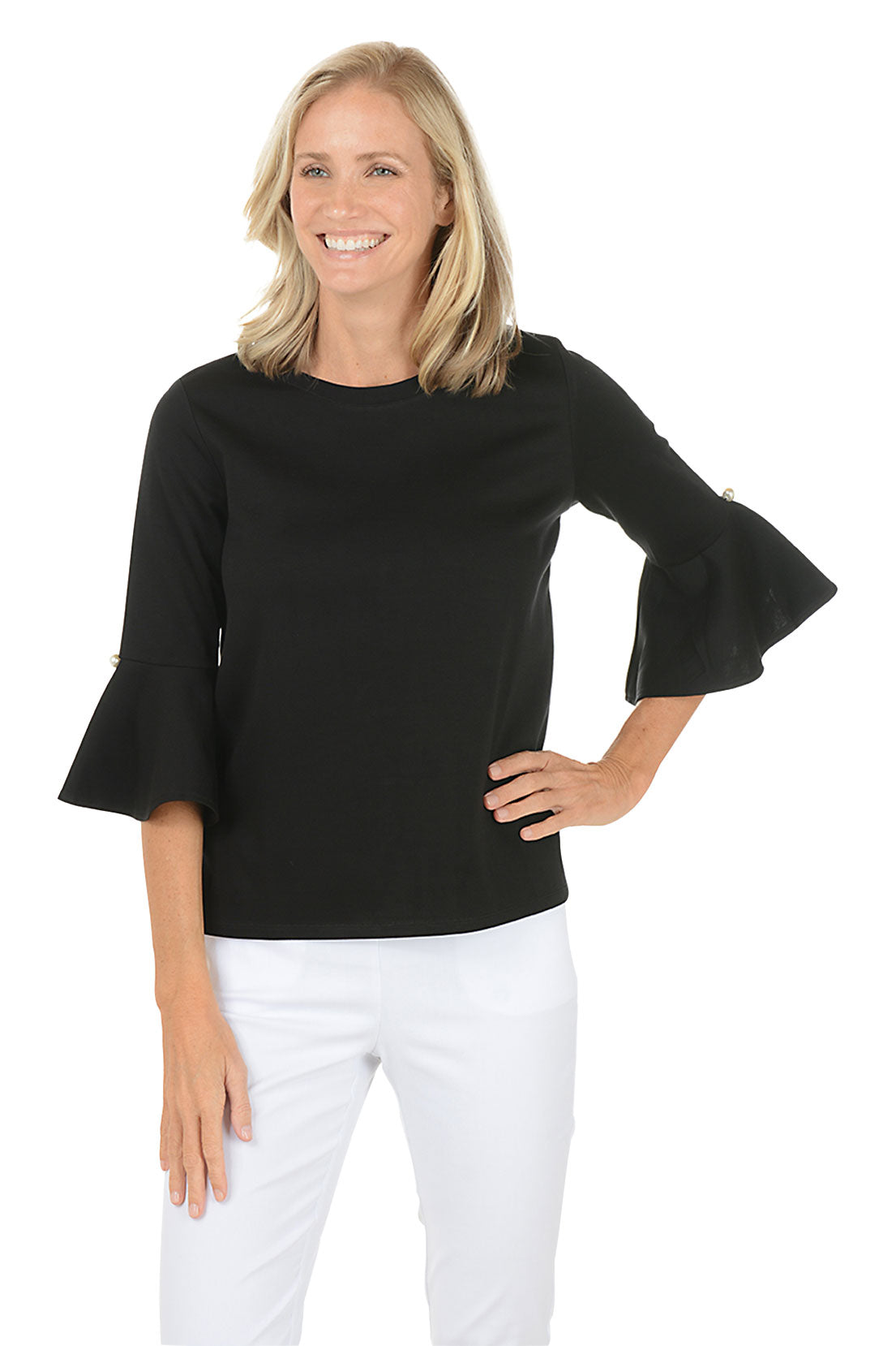 Woman wearing a black bell-sleeve top and white pants on a white background.