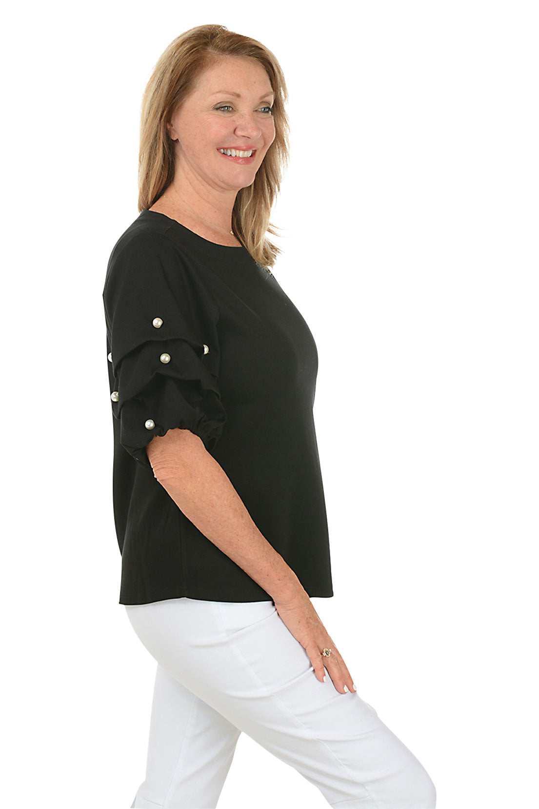 A side shot of a model wearing a black top with a scoop neck and pearl gathered elbow sleeves with embellishments. She is also wearing white pants.