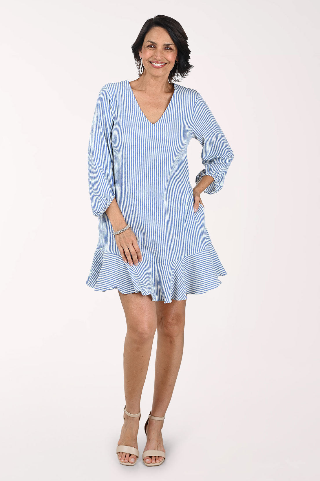 Woman wearing a light blue and white striped dress on a white background