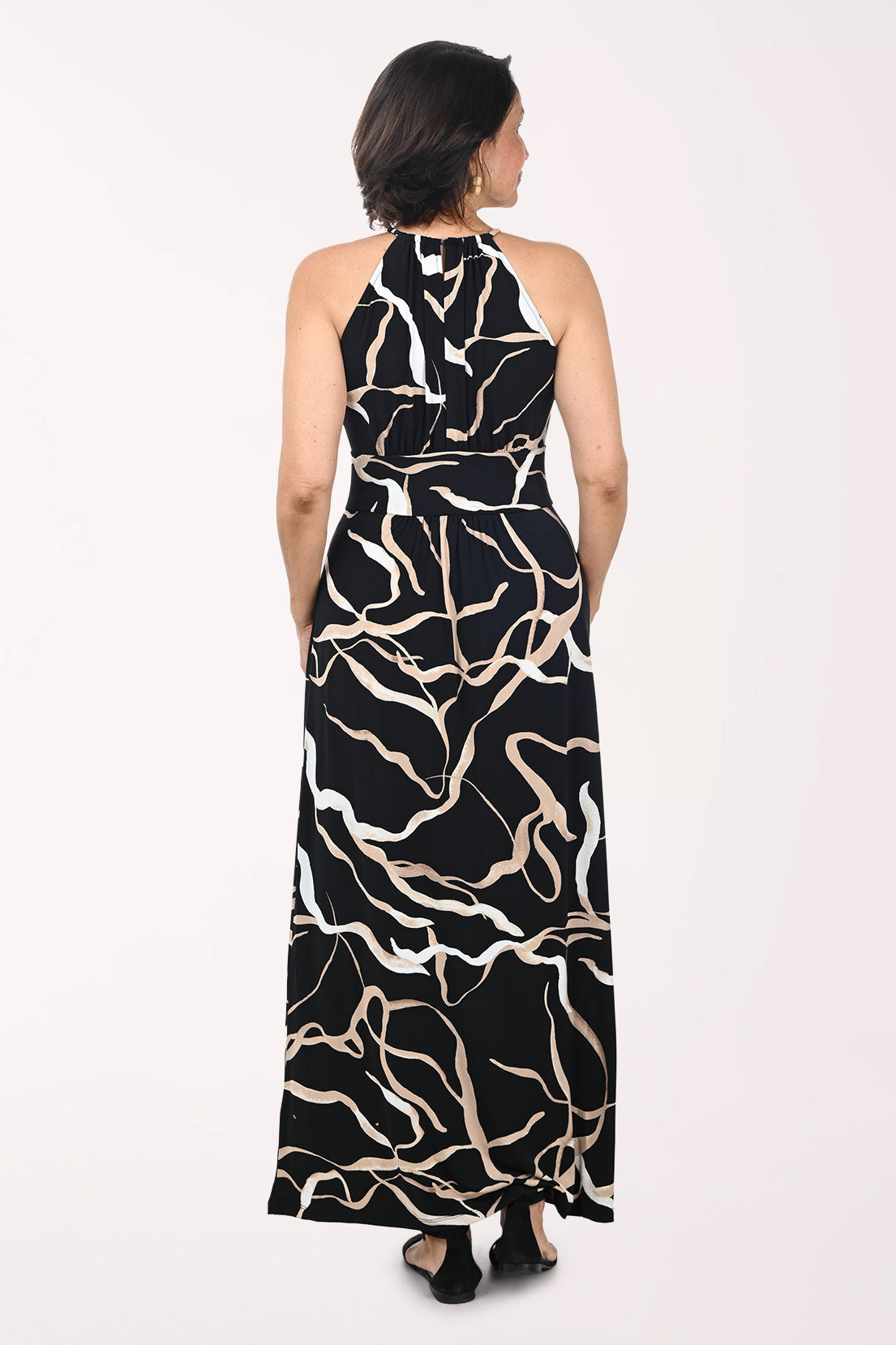 Woman wearing a black and beige patterned halter neck dress on a white background