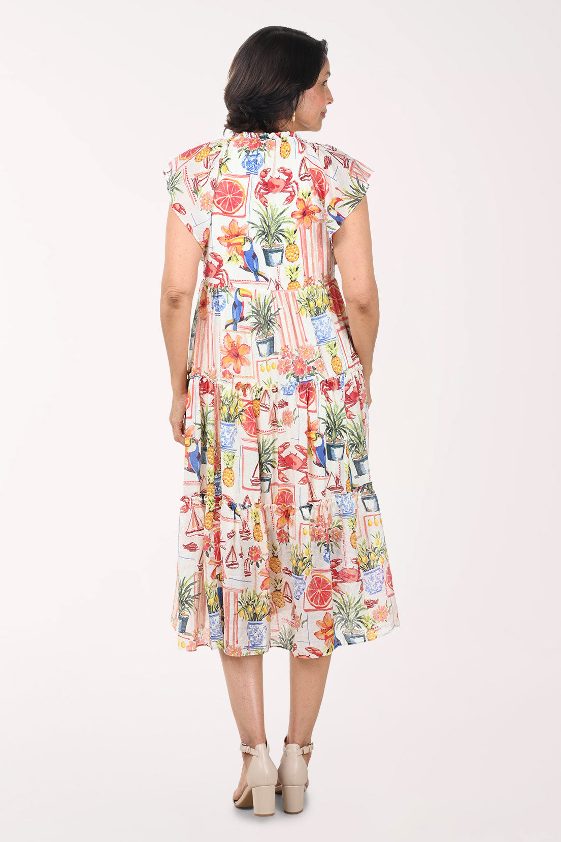 Woman wearing a colorful dress with a pattern of potted plants on a white background