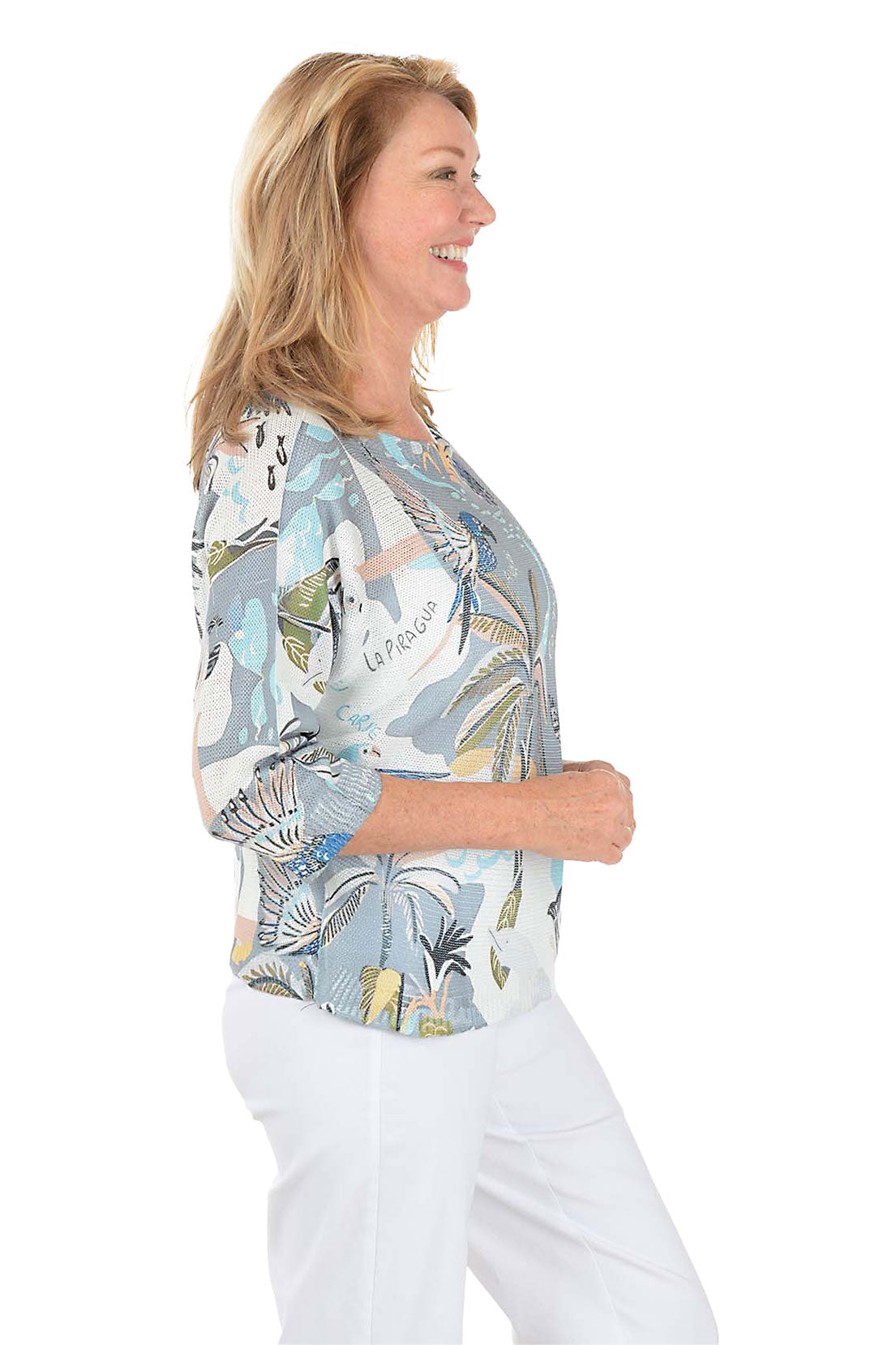 Woman wearing a patterned blouse with a white background. Side shot.