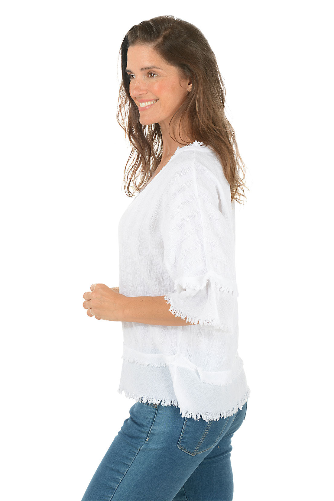 Woman wearing a white blouse with ruffled details on a white background. Side shot.