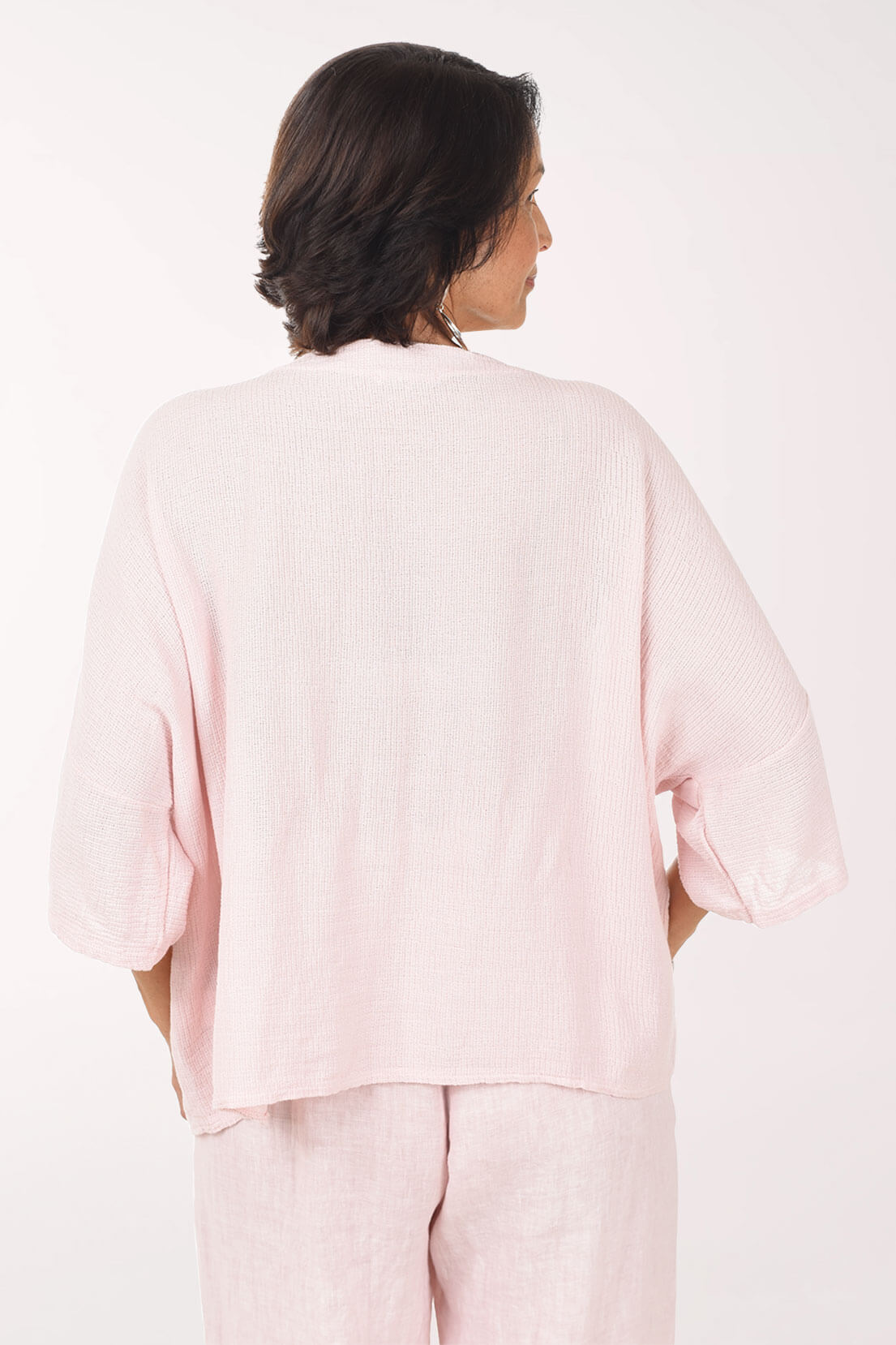 Woman wearing a light pink outfit on a white background - back shot