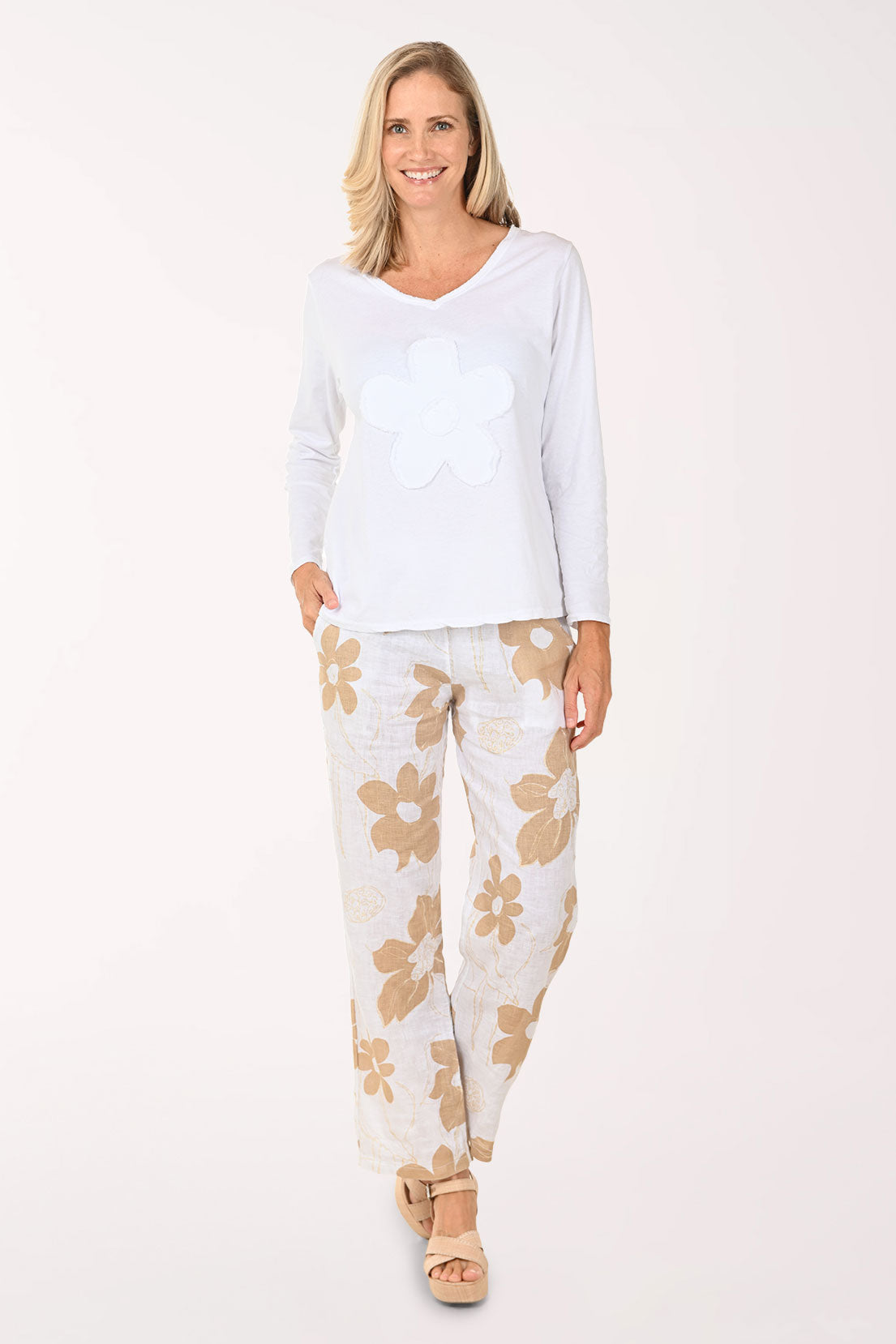 Woman wearing a white top and floral pants on a white background
