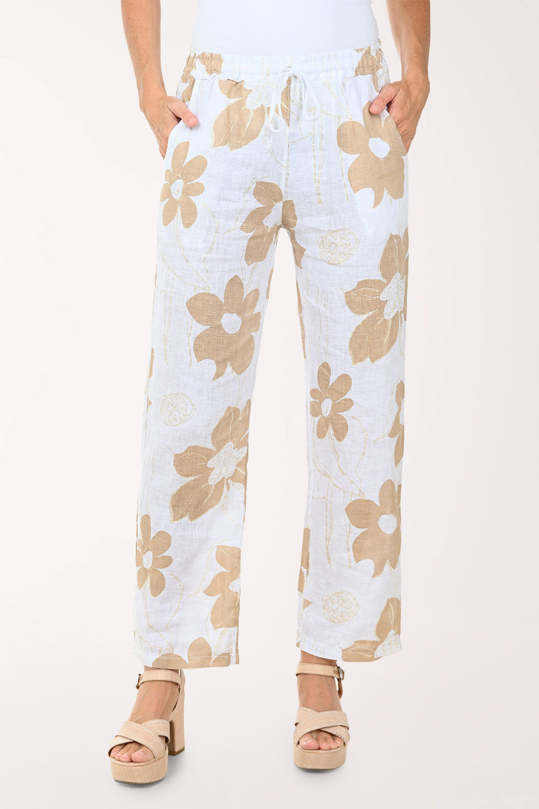 Woman wearing a white top and floral pants on a white background