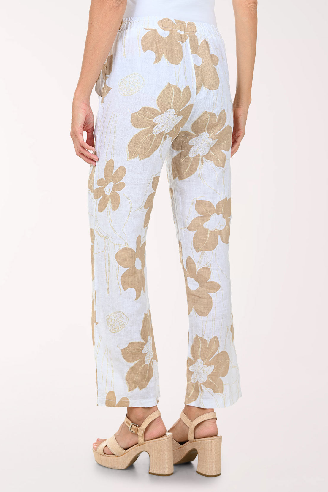 Woman wearing a white top and floral pants on a white background